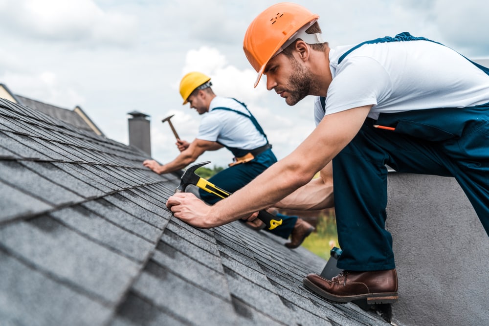Selective Focus Of Handyman Repairing Roof With Coworker.