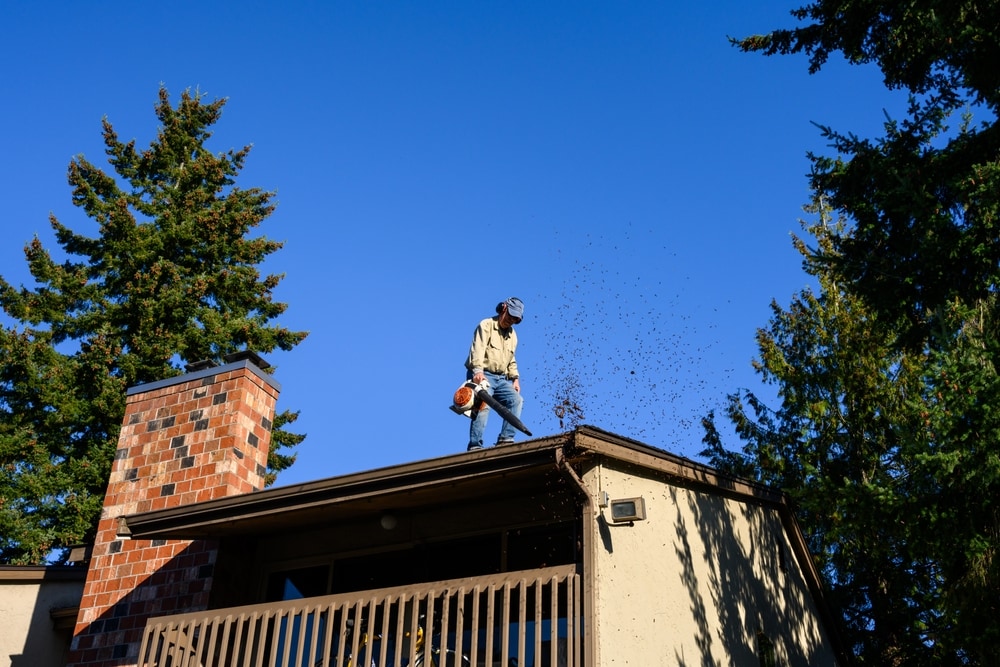 Senior Man With Gas Powered Leaf Blower Cleaning Roof Gutters