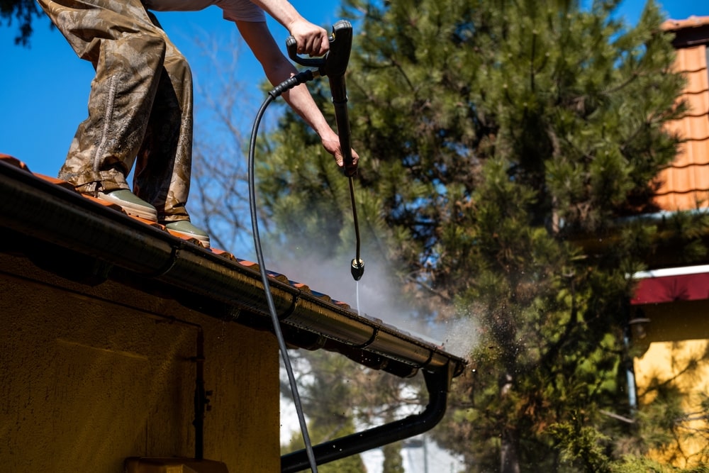 Spring Rain Gutters Cleaning Using Pressure Washer. Closeup Photo.