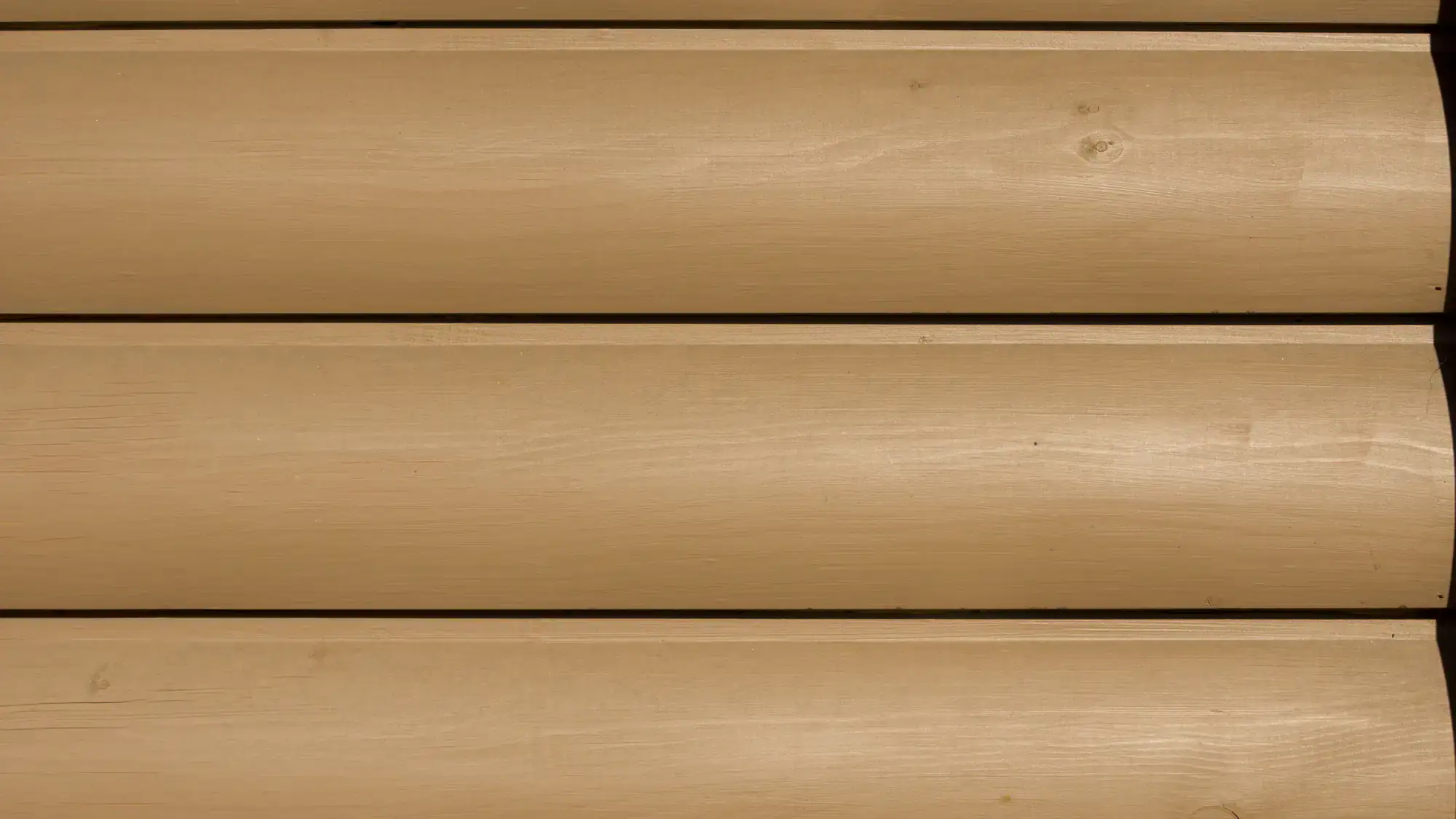 Close-up view of a wood log wall with horizontal beige wooden planks, showing a smooth, polished texture and subtle wood grain patterns.