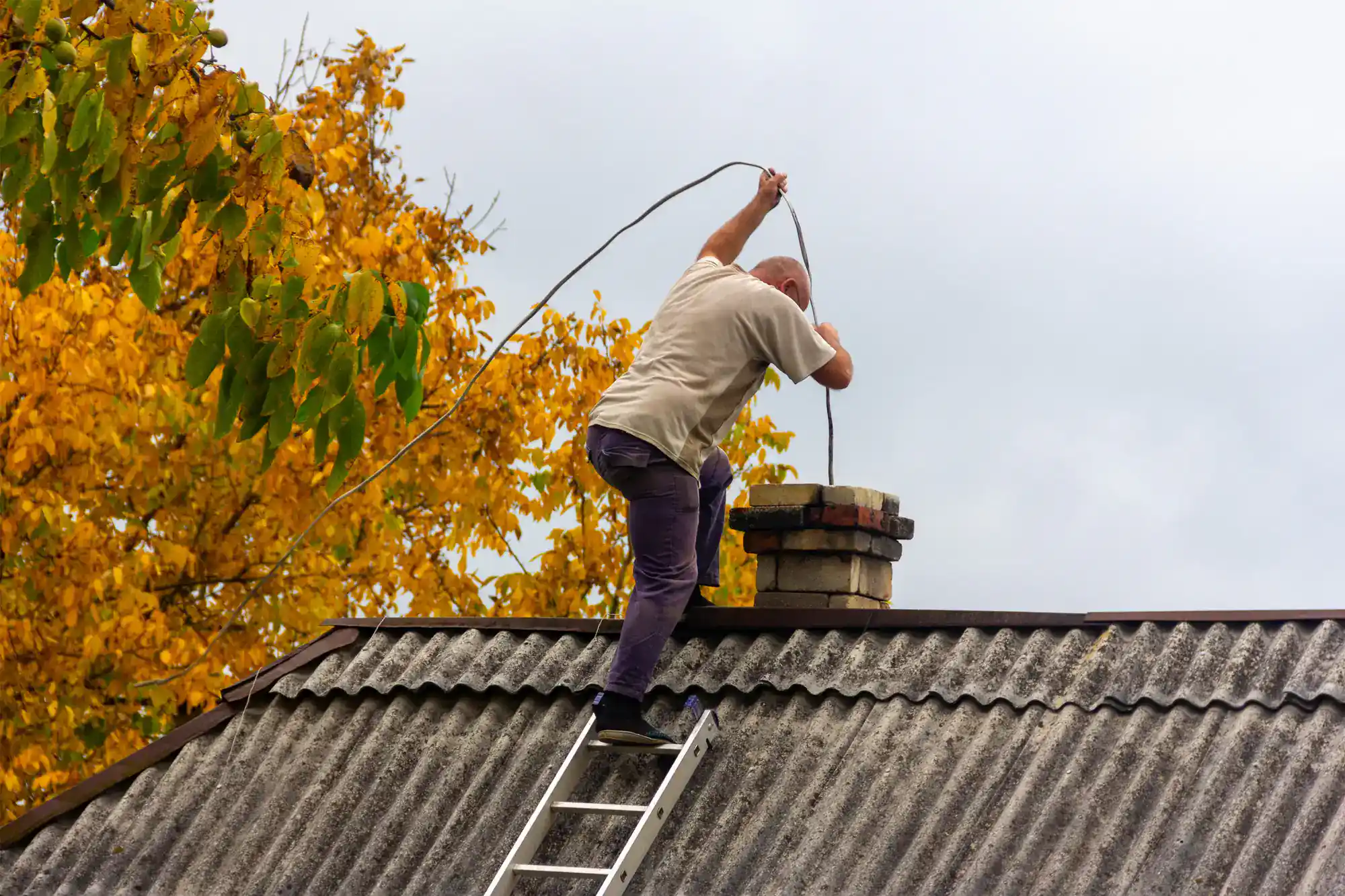 Chimney cleaning in action on a rooftop in Suffolk County, NY, with a professional technician from SkyLuxe Construction performing maintenance