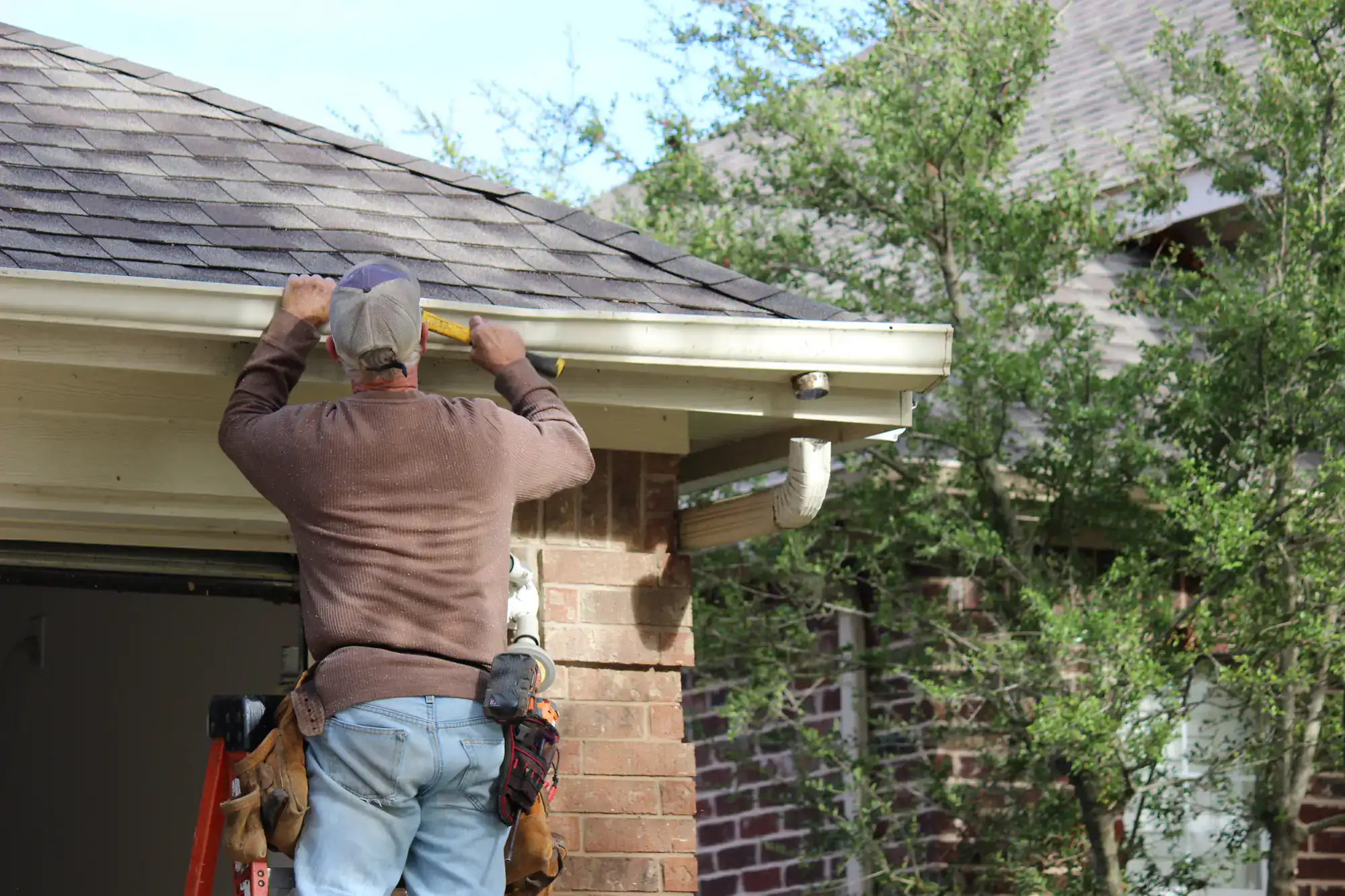 SkyLuxe Construction worker on a ladder performing gutter repair in Suffolk County, NY, ensuring efficient water flow and protecting the home's exterior